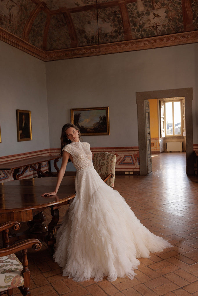 Bride wearing Wona Concept Mars Ivory wedding dress in dining room with ruffle layers sold by le reve boutique st albert alberta